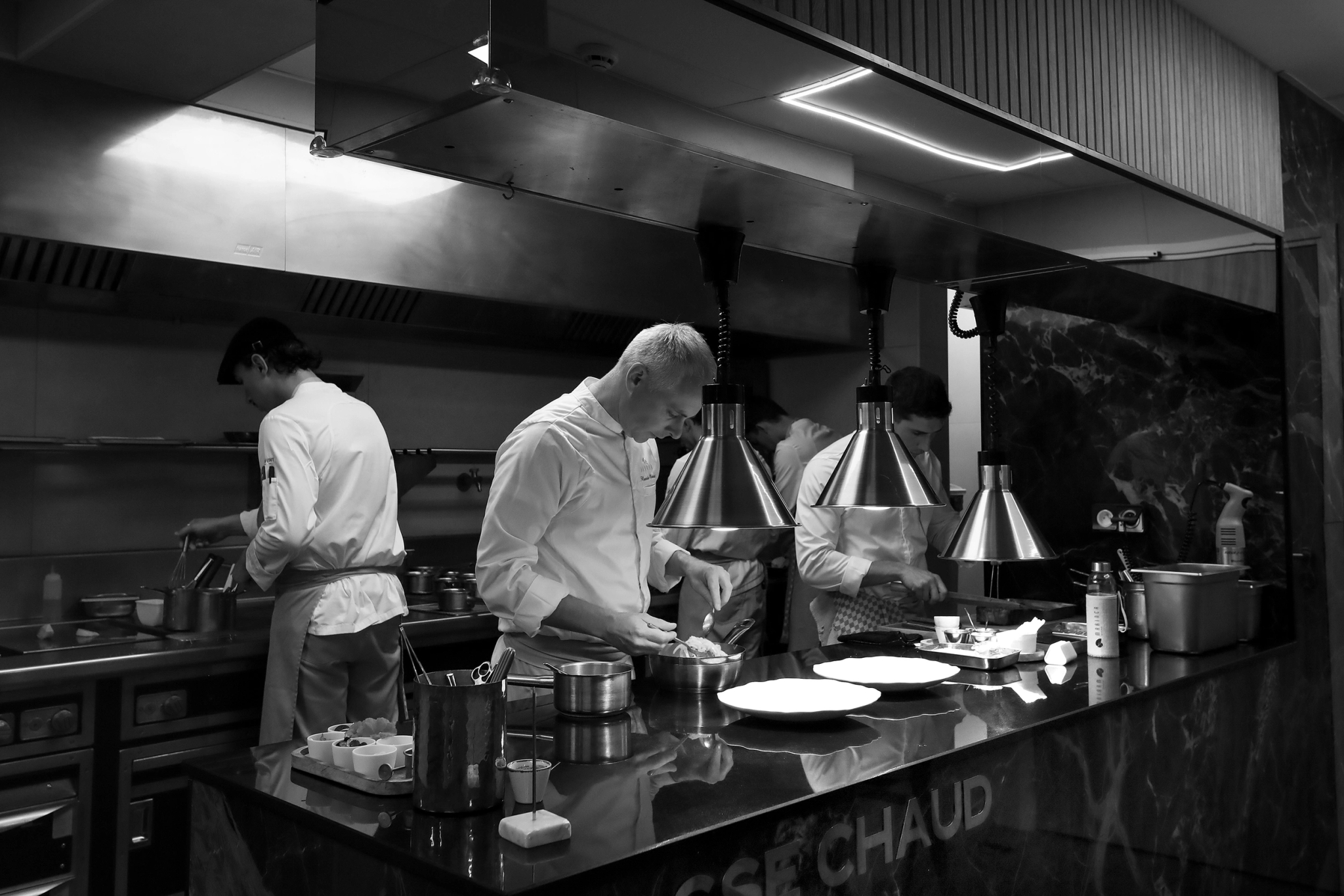 Chef cuisinier préparant un plat en cuisine professionnelle avec son équipe