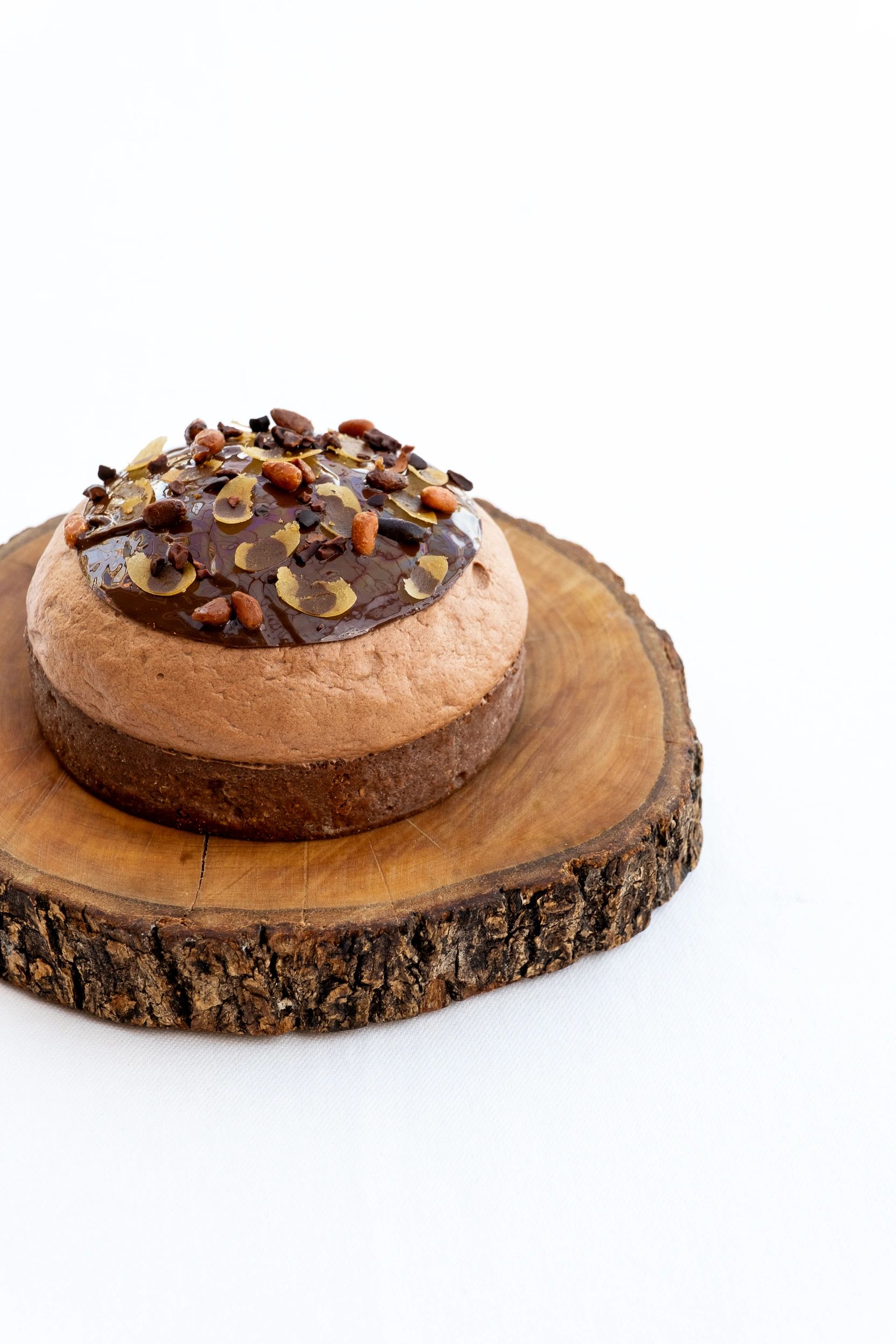 Gâteau au chocolat avec glaçage et amandes grillées sur socle en bois naturel