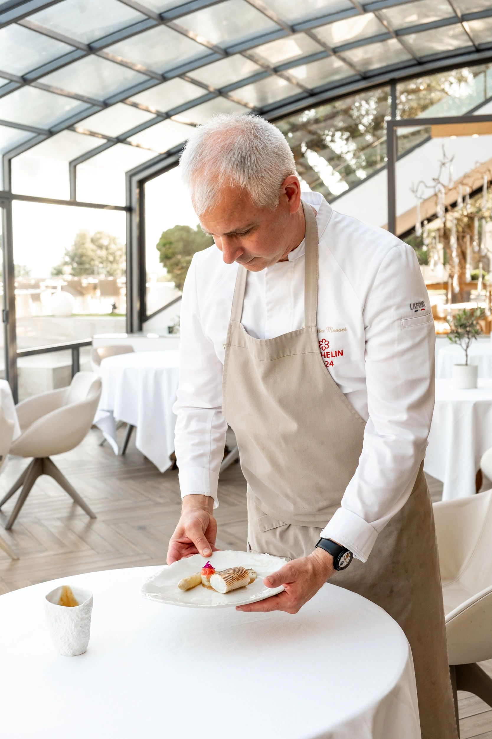 Chef étoilé Michelin présentant un plat gastronomique en salle de restaurant