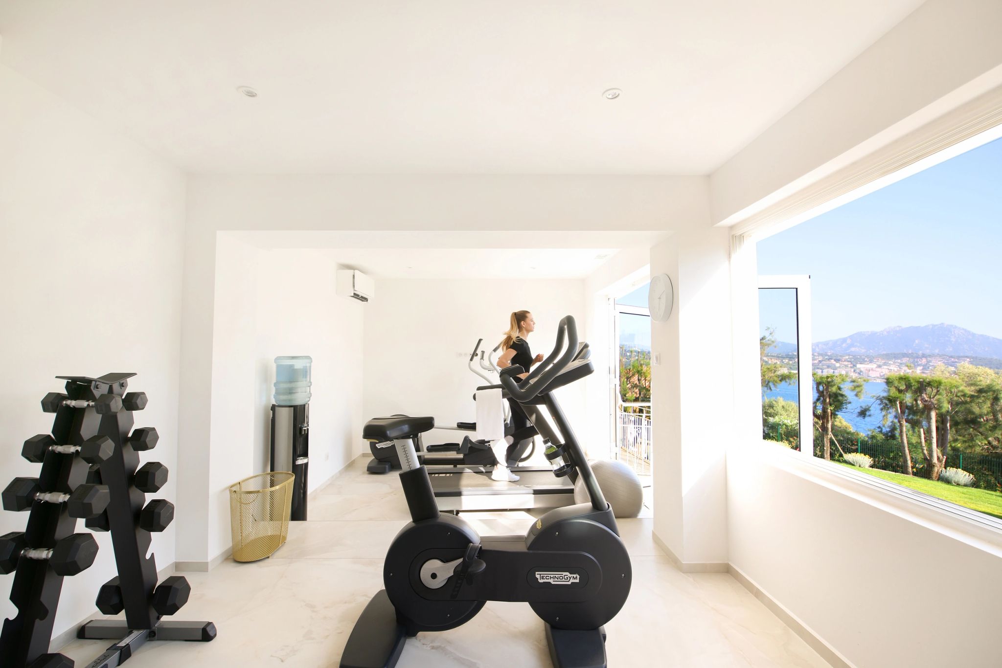 Salle de fitness moderne avec équipements de sport, haltères et vélos d'exercice face à une vue panoramique