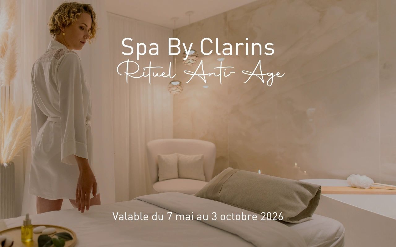 Spa By Clarins Rituel Anti-Âge avec femme en peignoir blanc dans un salon de spa luxueux disponible mai octobre 2026
