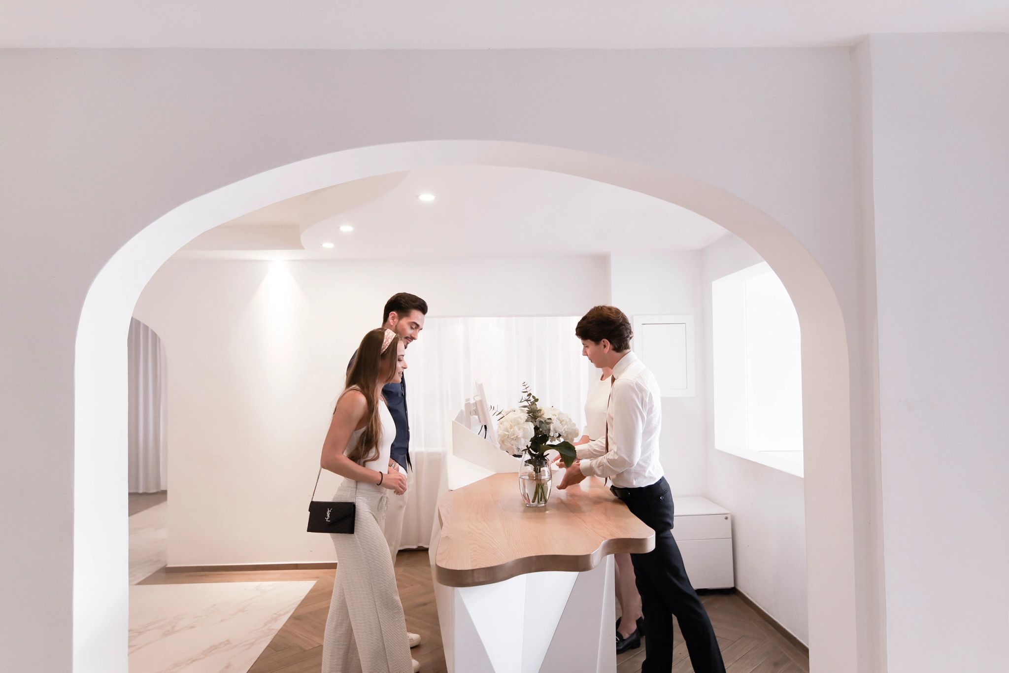 Couple visitant un showroom moderne avec une femme consultant sur un meuble design blanc