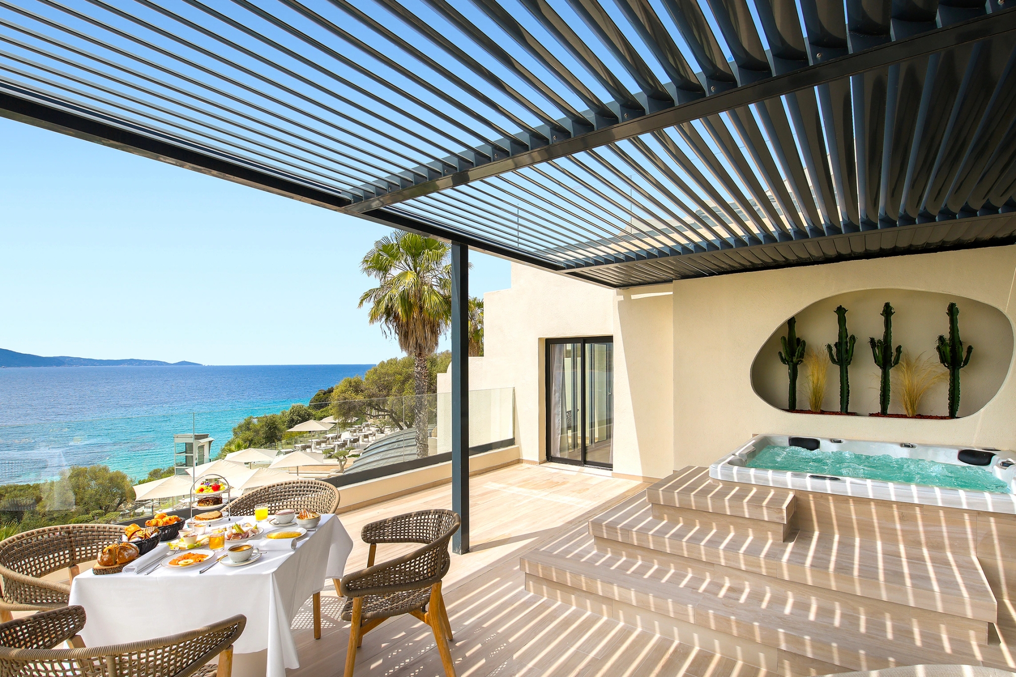 Terrasse méditerranéenne avec jacuzzi, table de petit-déjeuner et vue panoramique sur la mer bleue