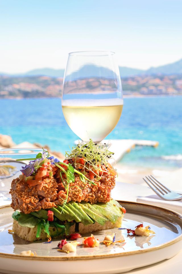 Burger gourmet avec verre de vin blanc face à la mer méditerranéenne en restaurant de luxe