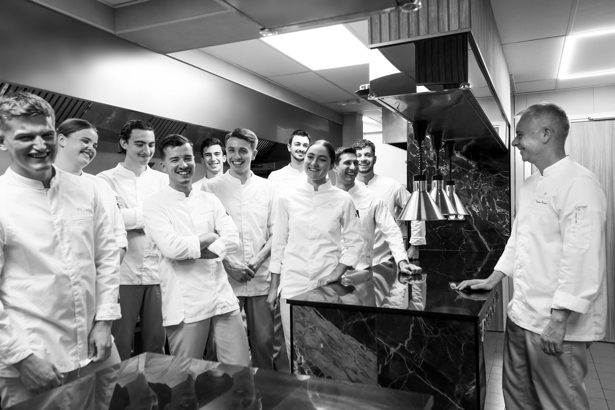 Équipe de chefs cuisiniers en vêtements blancs posant ensemble dans une cuisine professionnelle moderne
